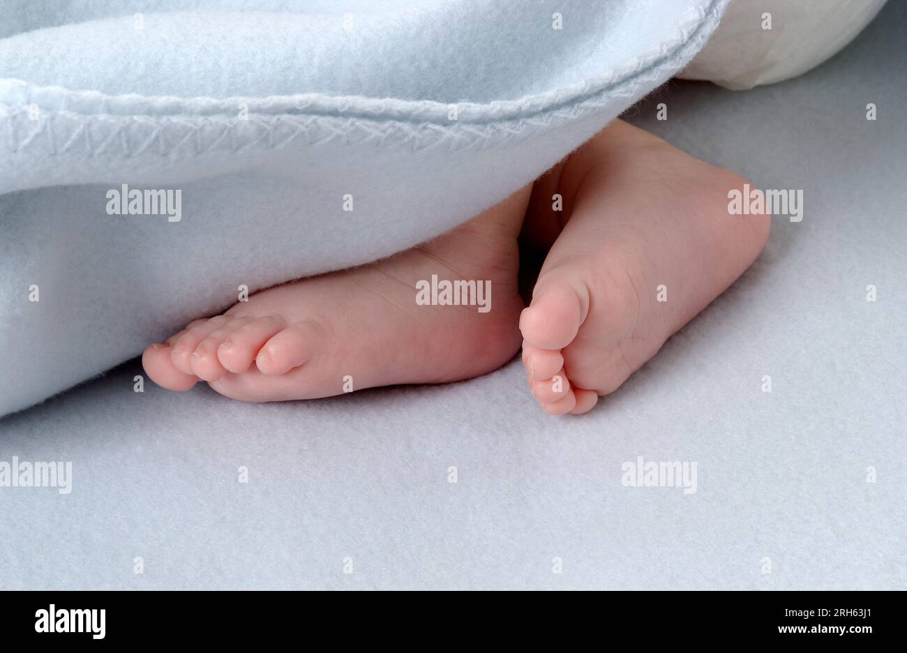 Paire de petits pieds de bébé nouveau-né se ferment sous une couverture dans le lit Banque D'Images