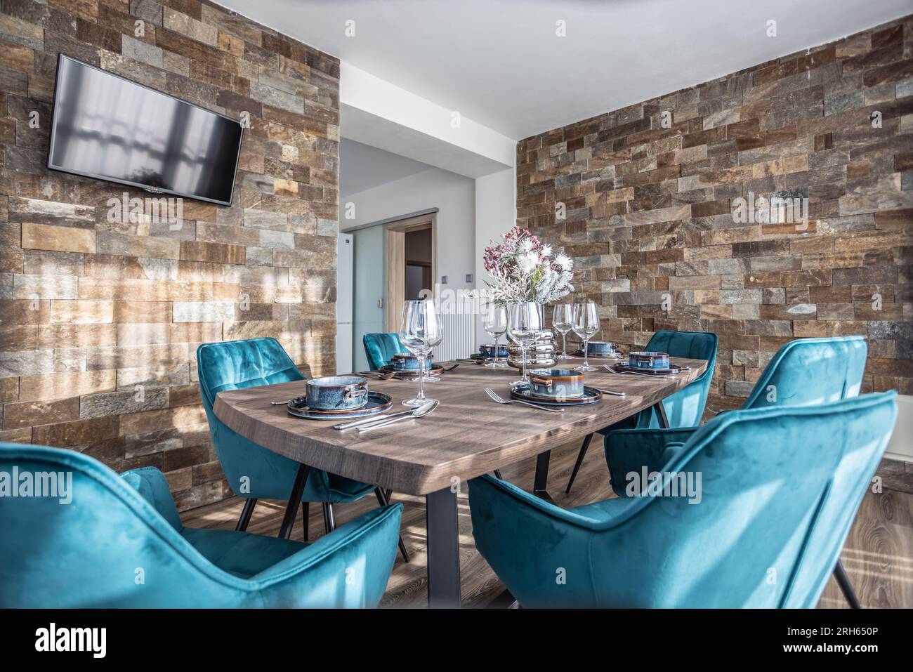Salle à manger avec table en bois et chaises bleues au sol dans un appartement moderne. Banque D'Images