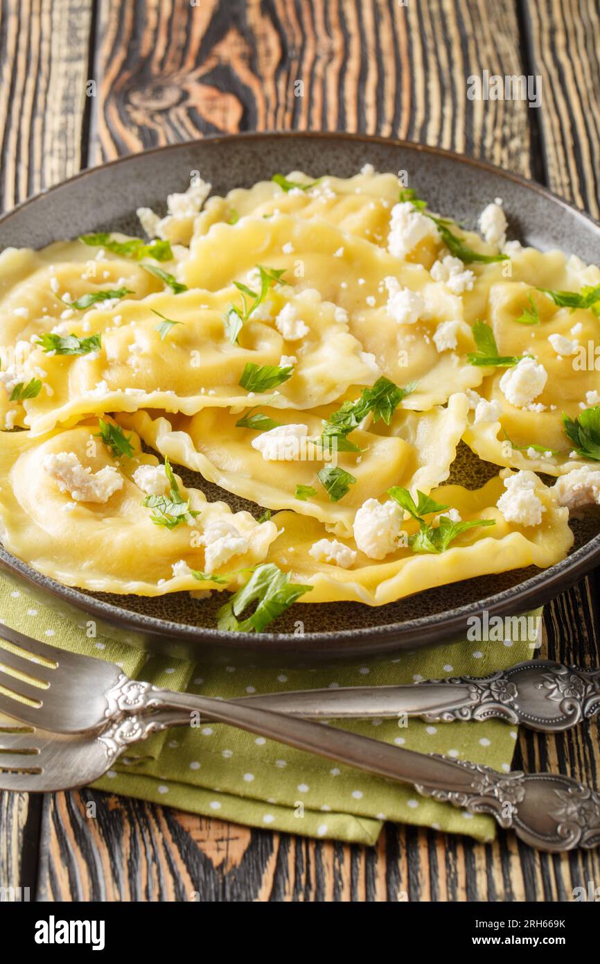 Boulettes de mezzaluna italiennes en forme de croissant farcies de fromage et d'herbes en gros plan dans une assiette sur la table. Vertical Banque D'Images