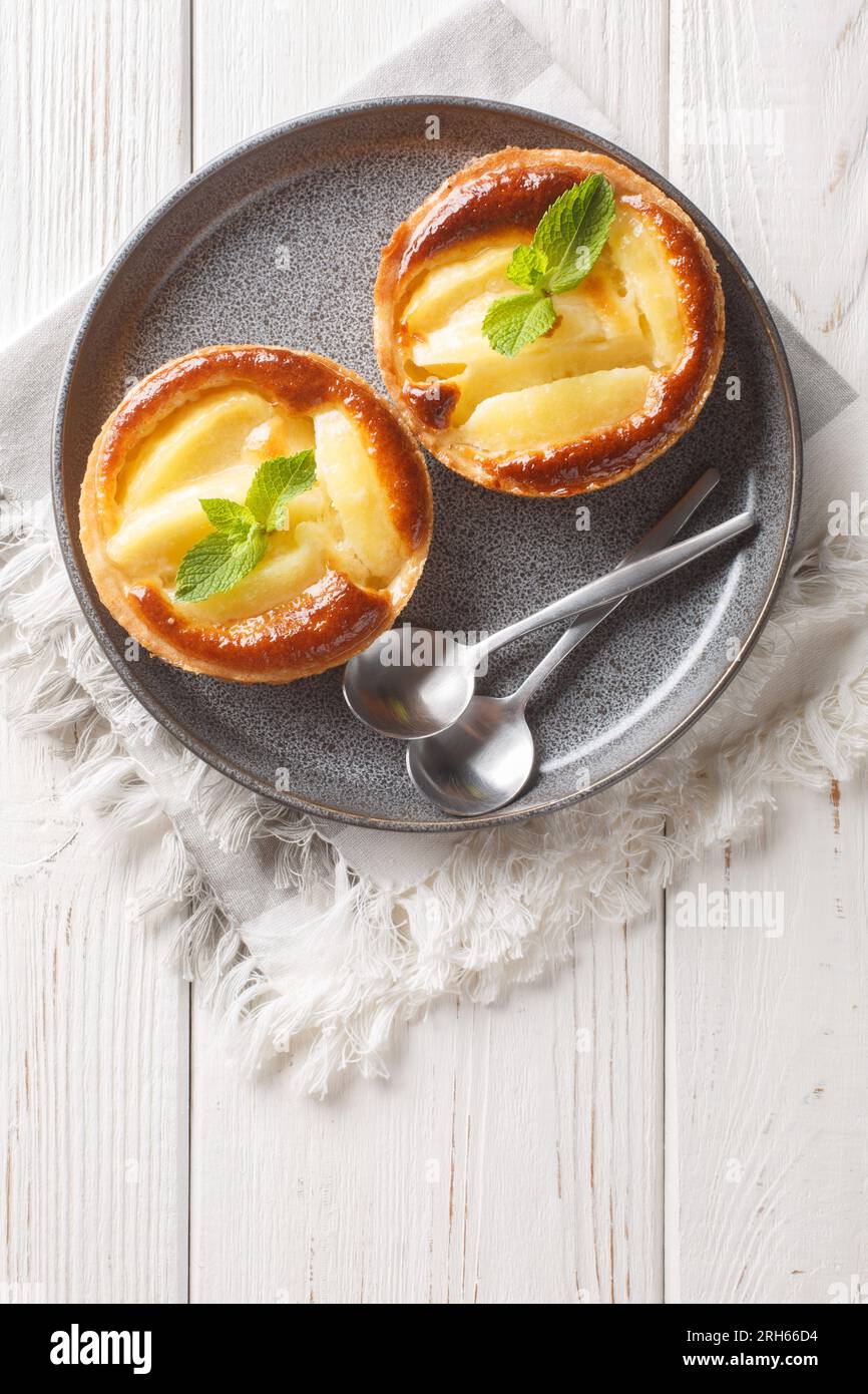 Tartelette aux pommes cuite classique avec crème anglaise et gros plan à la menthe dans une assiette sur la table. Vue verticale de dessus Banque D'Images