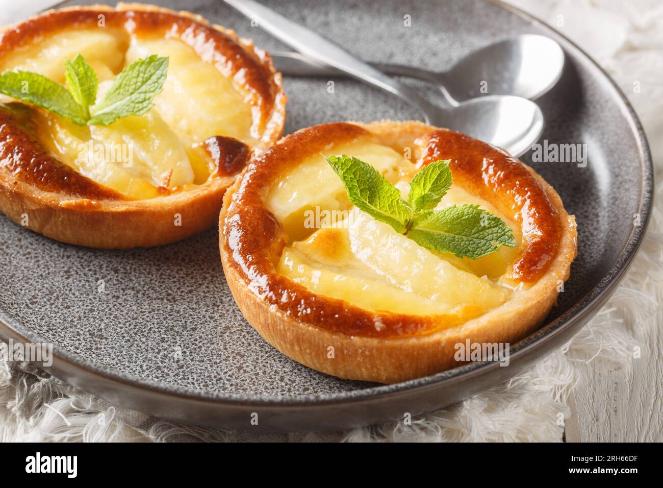 Tartelettes de pommes portionnées françaises décorées de menthe en gros plan dans une assiette sur la table. Horizontal Banque D'Images