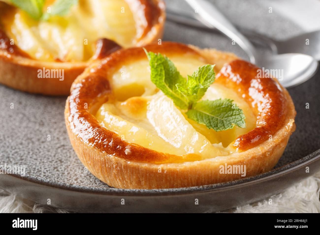 Tartelette aux pommes cuite classique avec crème anglaise et gros plan à la menthe dans une assiette sur la table. Horizontal Banque D'Images