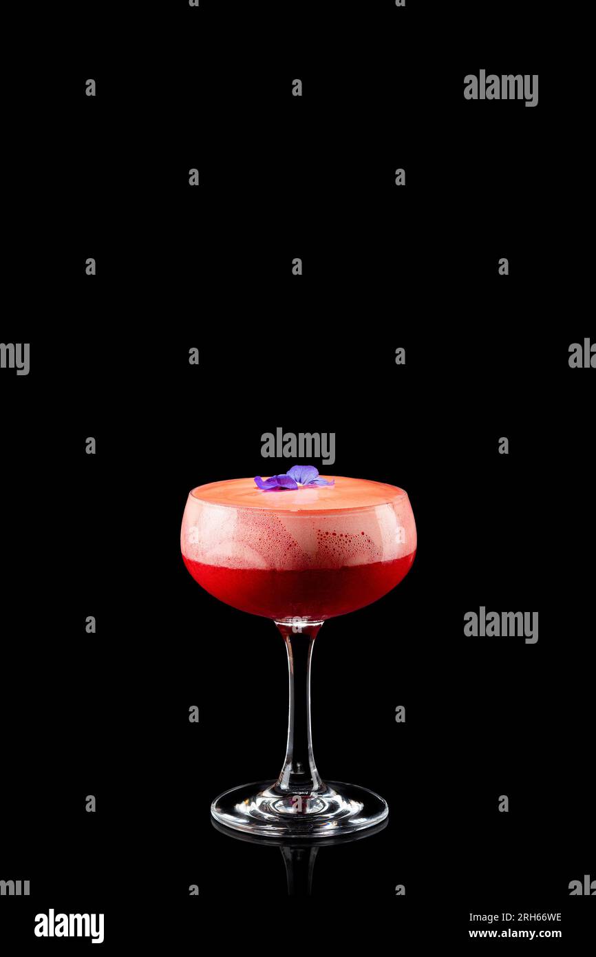 Cocktail margarita fraise congelée fruitée avec fleur violette isolé sur un fond noir. Cocktail alcoolisé frais. Banque D'Images