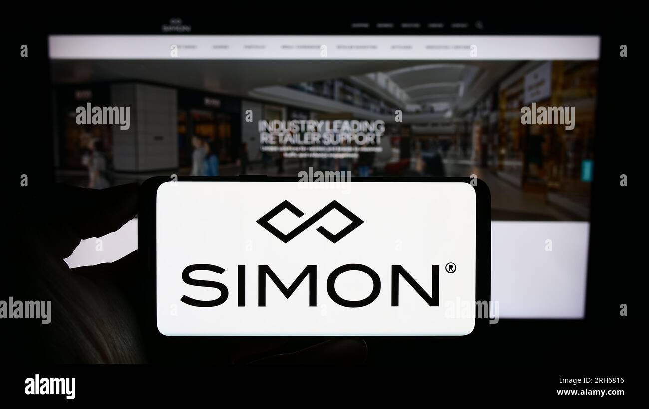 Personne détenant un smartphone avec le logo de la société immobilière américaine Simon Property Group Inc. Sur l'écran devant le site Web. Concentrez-vous sur l'affichage du téléphone. Banque D'Images
