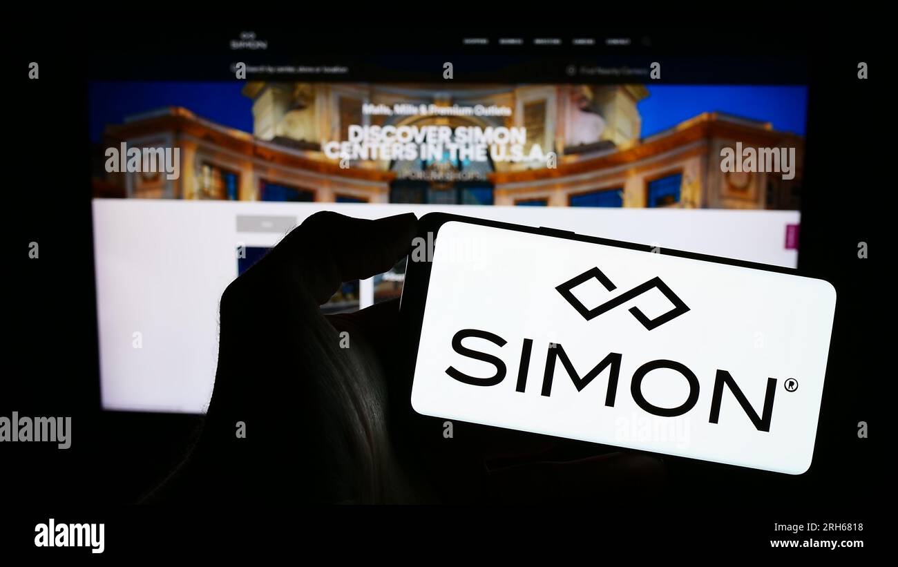 Personne détenant le téléphone cellulaire avec le logo de la société immobilière américaine Simon Property Group Inc. Sur l'écran devant la page Web. Concentrez-vous sur l'affichage du téléphone. Banque D'Images