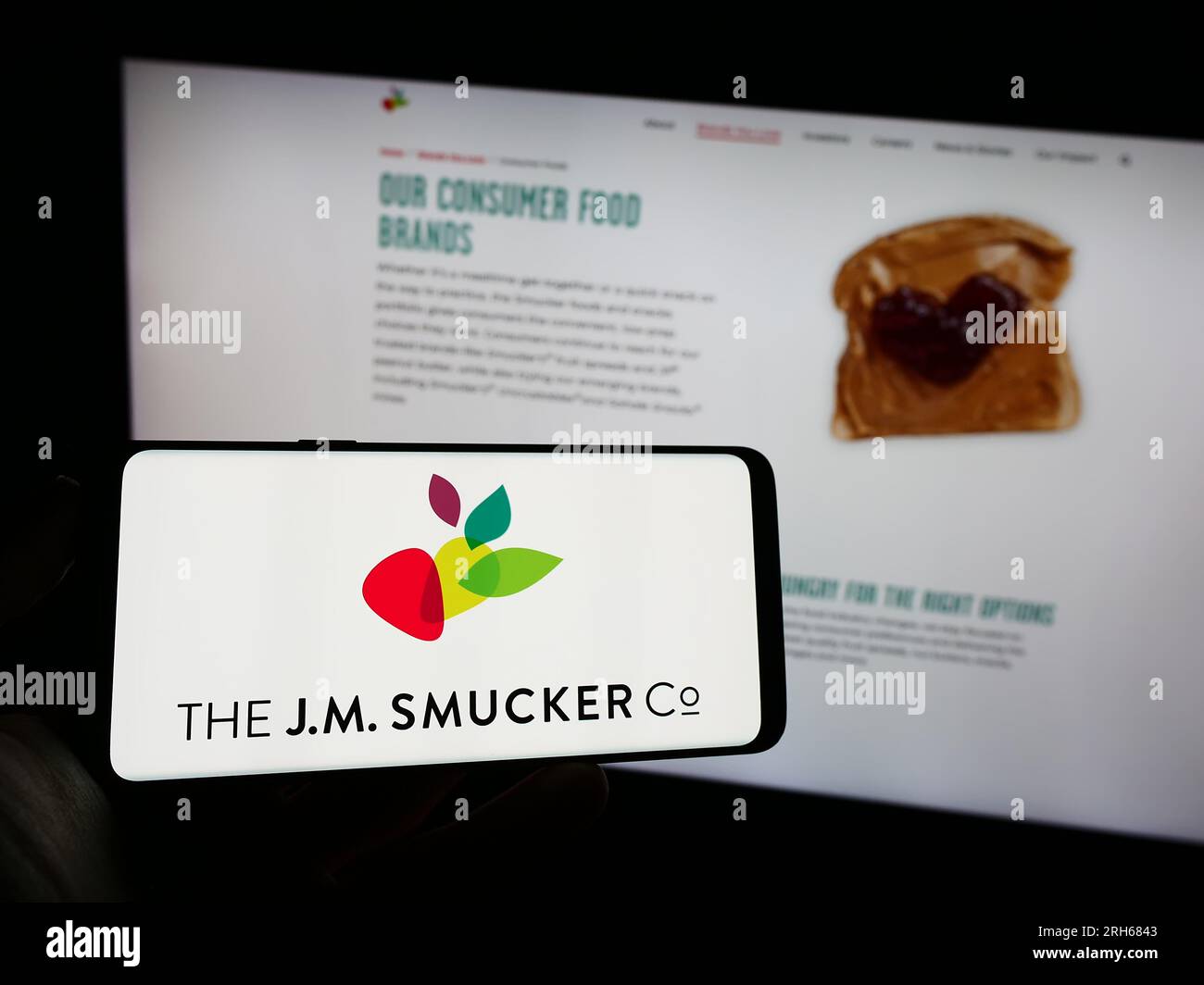 Personne tenant le téléphone portable avec le logo de l'entreprise alimentaire américaine la J.M. Smucker Company sur l'écran devant la page Web de l'entreprise. Concentrez-vous sur l'affichage du téléphone. Banque D'Images