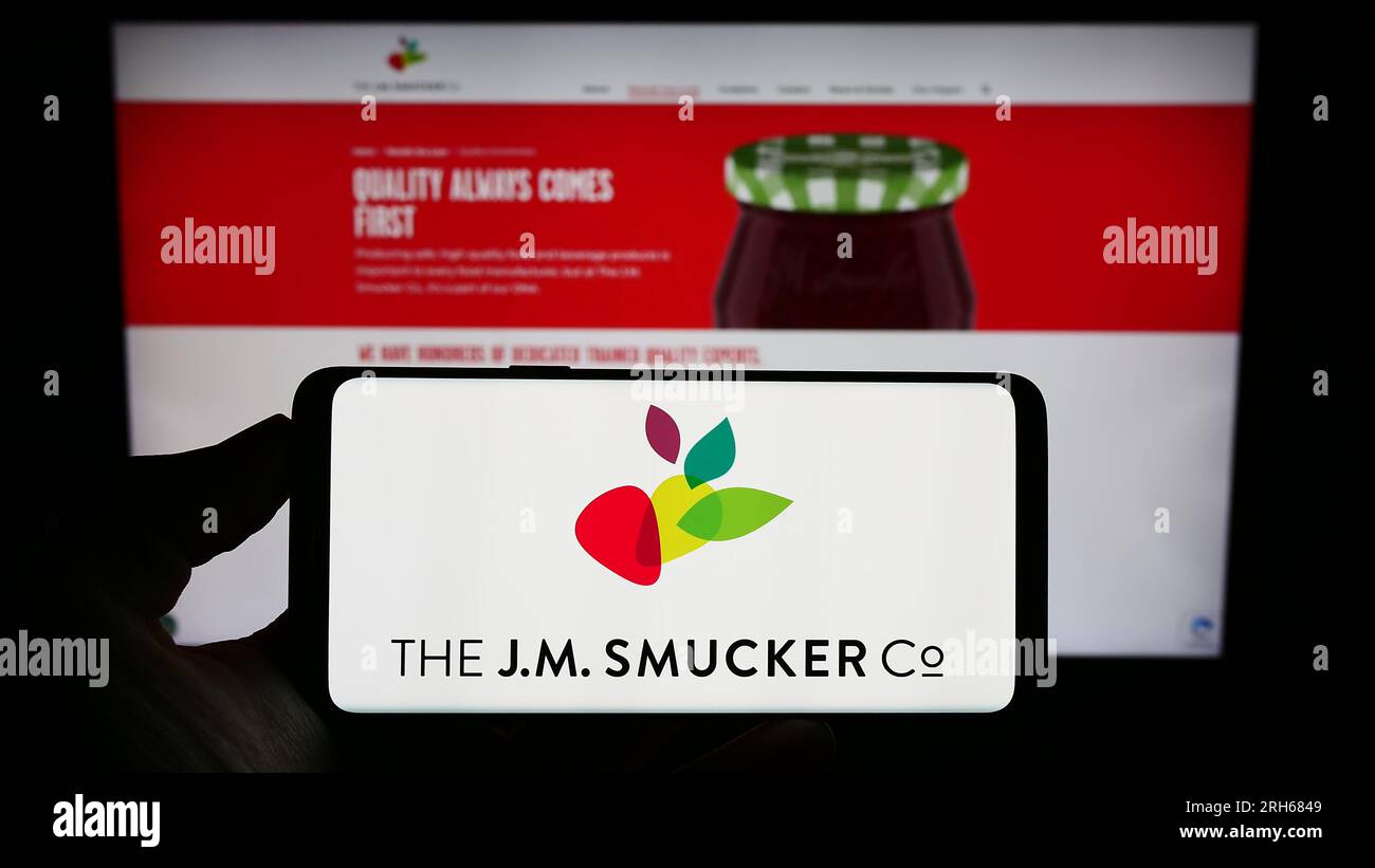 Personne tenant un smartphone avec le logo de l'entreprise alimentaire américaine J.M. Smucker Company sur l'écran en face du site Web. Concentrez-vous sur l'affichage du téléphone. Banque D'Images