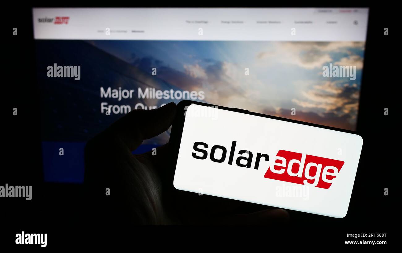 Personne tenant un téléphone cellulaire avec le logo de la société israélienne SolarEdge technologies Inc. Sur l'écran devant la page Web de l'entreprise. Concentrez-vous sur l'affichage du téléphone. Banque D'Images