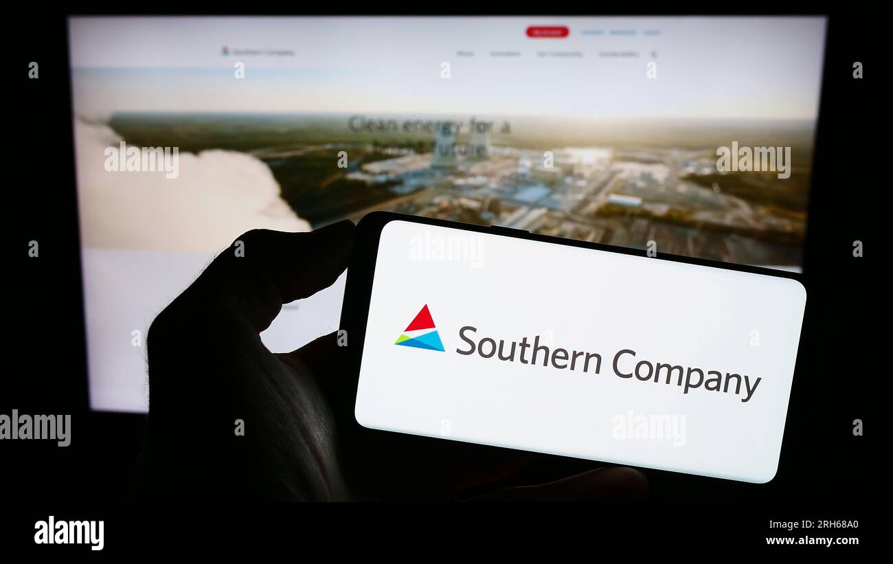 Personne tenant un smartphone avec le logo de l'entreprise de services publics américaine Southern Company sur l'écran devant le site Web. Concentrez-vous sur l'affichage du téléphone. Banque D'Images