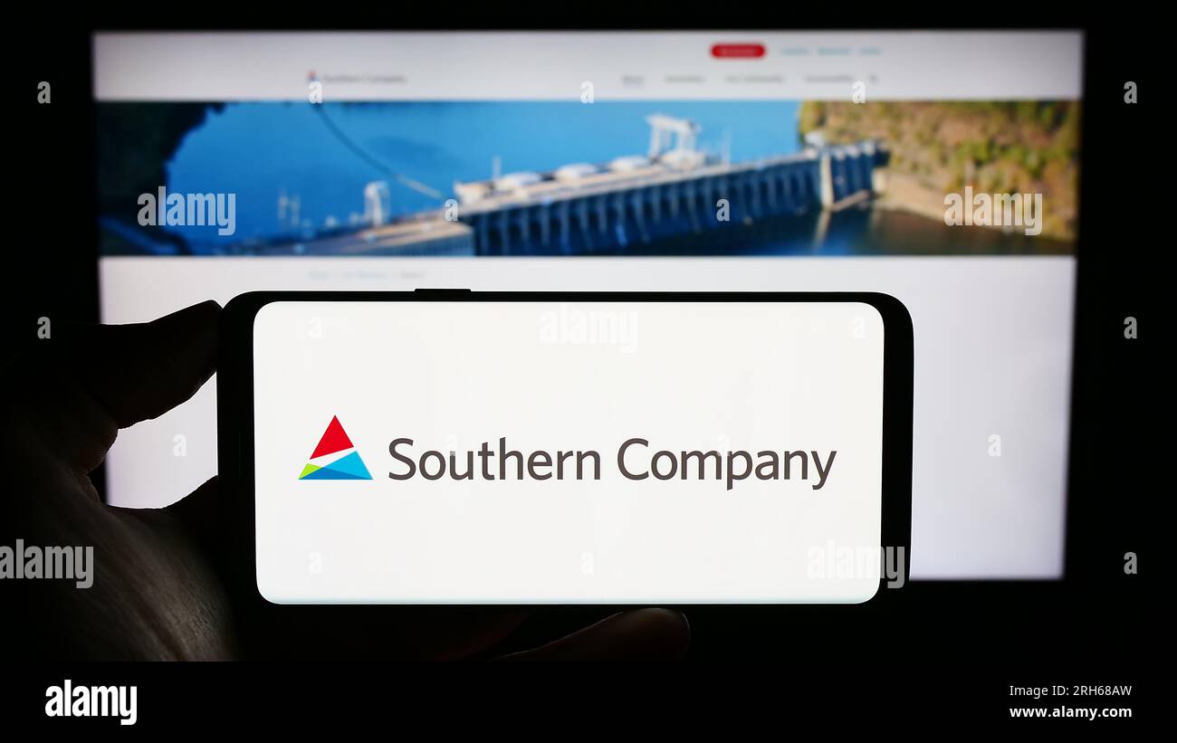 Personne tenant le téléphone portable avec le logo de l'entreprise de services publics américains Southern Company sur l'écran en face de la page Web. Concentrez-vous sur l'affichage du téléphone. Banque D'Images
