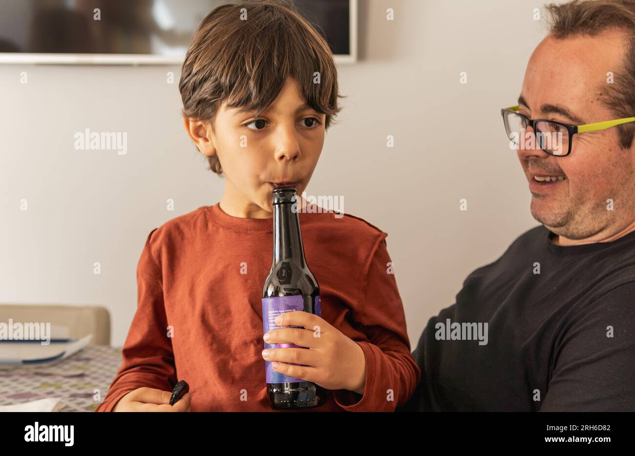 Garçon latin et son oncle jouant ensemble avec une bouteille pendant le repas de famille Banque D'Images