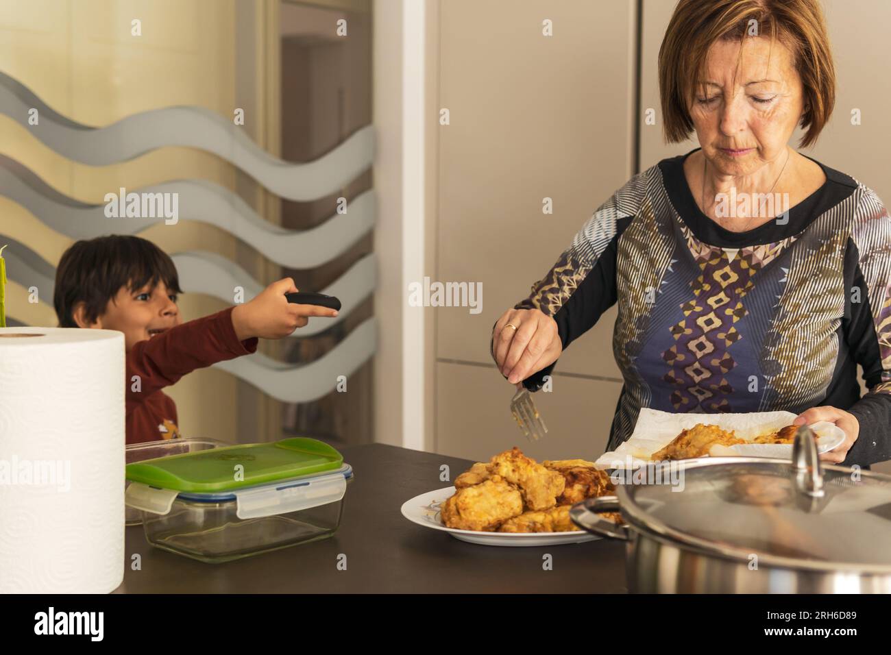 Heureux garçon latin parlant avec sa grand-mère dans la cuisine Banque D'Images