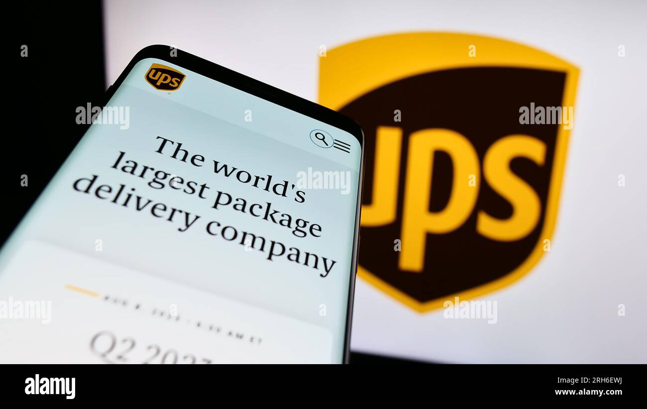 Smartphone avec page Web de la société américaine United Parcel Service Inc. (UPS) à l'écran devant le logo de l'entreprise. Effectuez le focus sur le coin supérieur gauche de l'écran du téléphone. Banque D'Images