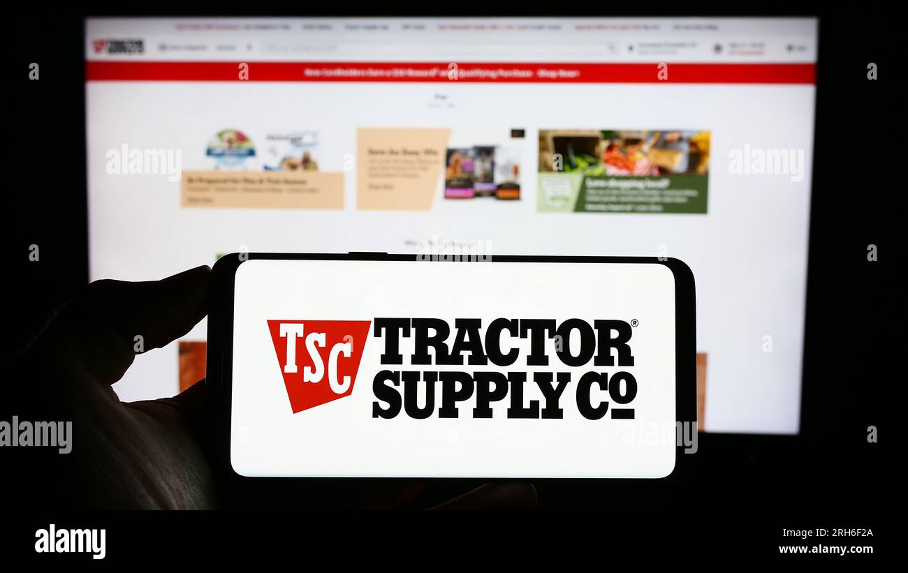 Personne tenant le téléphone portable avec le logo de l'entreprise de détail américaine Tractor Supply Company sur l'écran en face de la page Web de l'entreprise. Concentrez-vous sur l'affichage du téléphone. Banque D'Images