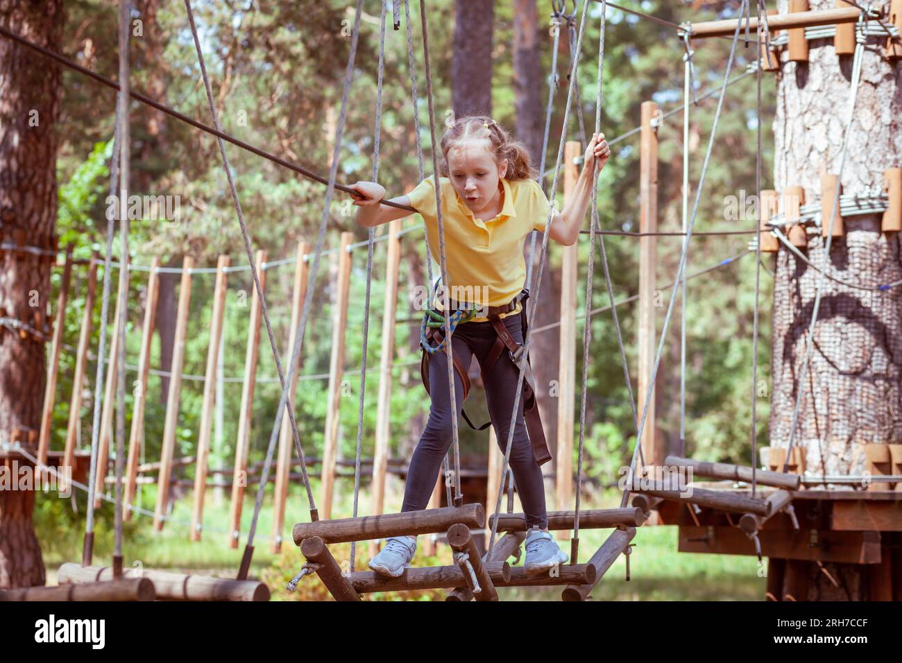 Enfant dans un parc d'aventure forestier fait de cordes. Centre de divertissement pour enfants en plein air. Aire de jeux pour enfants et sports avec téléphérique. Banque D'Images