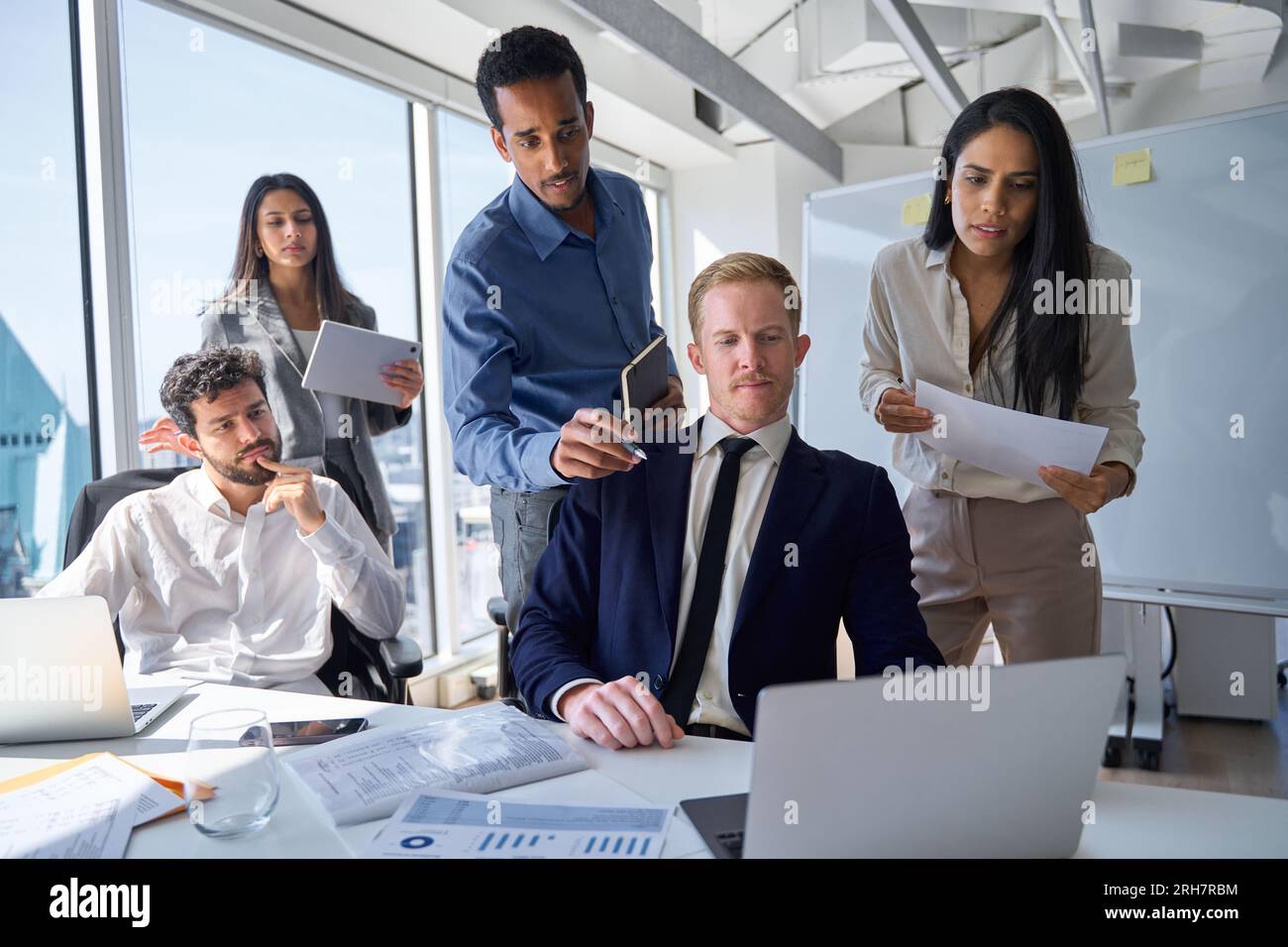 Groupe de cadres professionnels très occupés qui cherchent un ordinateur portable au bureau. Banque D'Images
