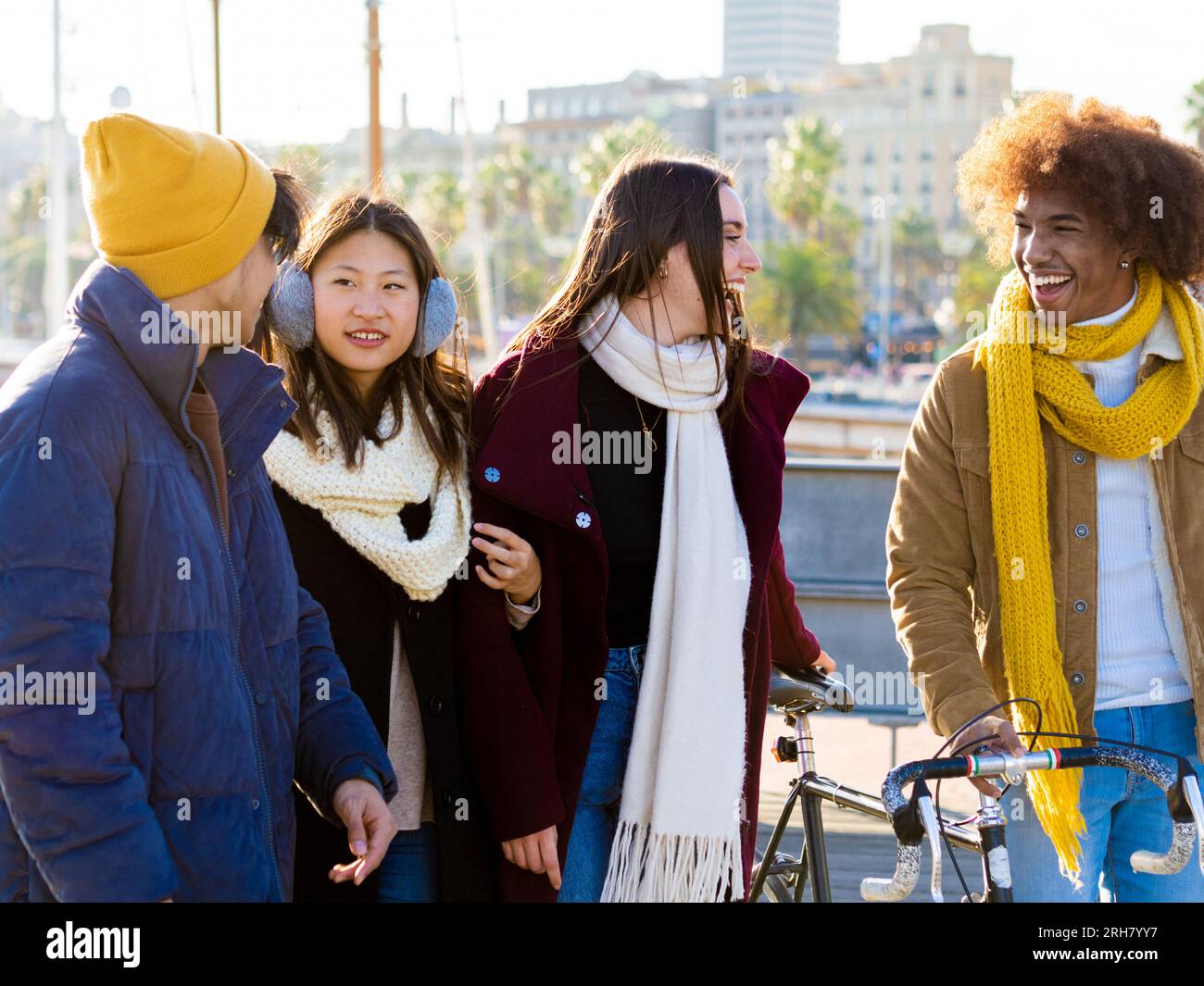 Groupe d'amis divers en vêtements d'hiver marchent ensemble dans la ville bavardant les uns avec les autres Banque D'Images