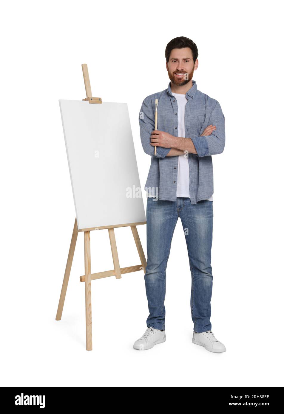 Homme heureux avec brosse près du chevalet avec toile sur fond blanc. Passe-temps créatif Banque D'Images