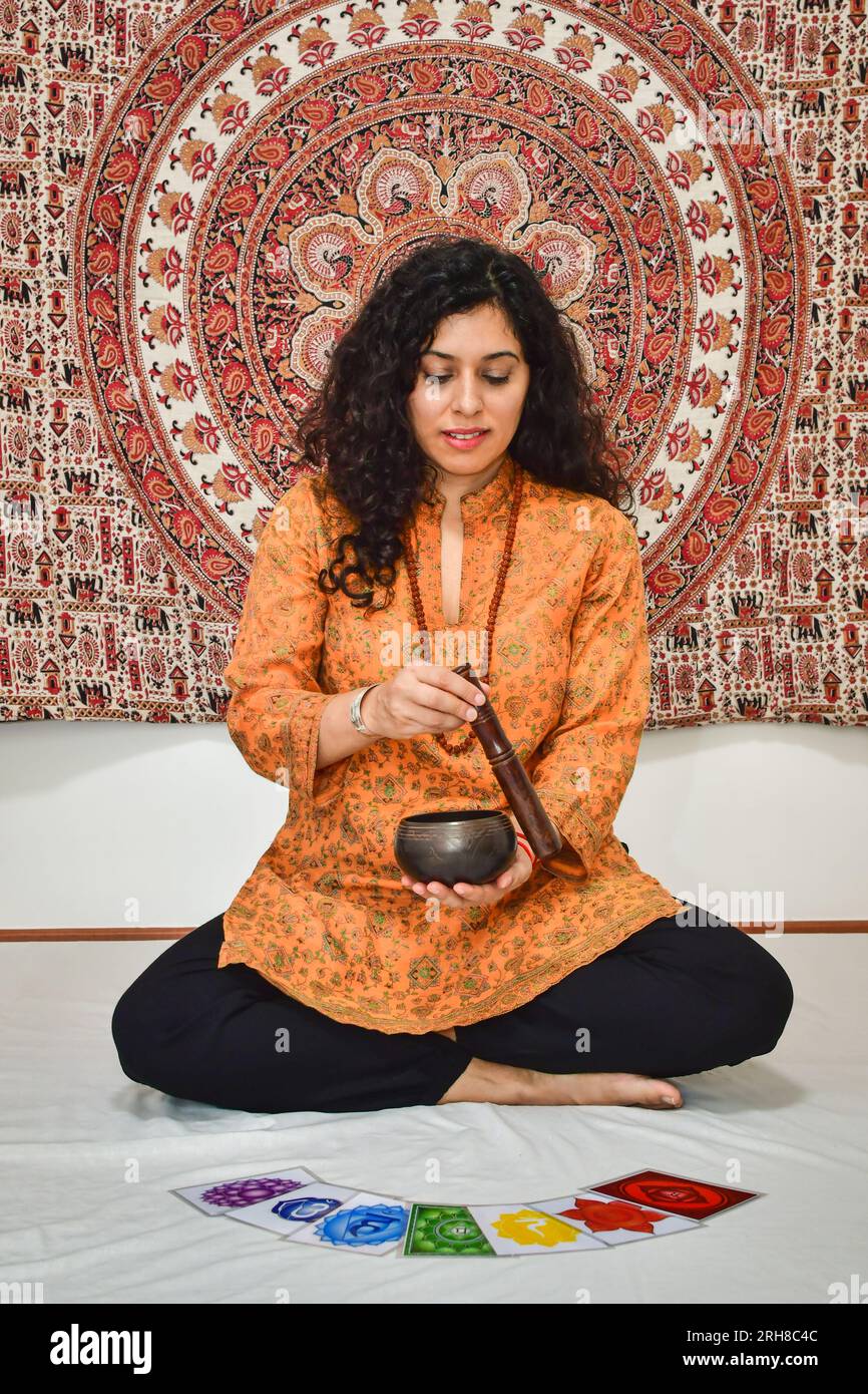 Une femme pratiquant la méditation et la guérison avec un bol chantant tibétain. Corps humain 7 images du système énergétique Chakras, méditation de yoga. Banque D'Images