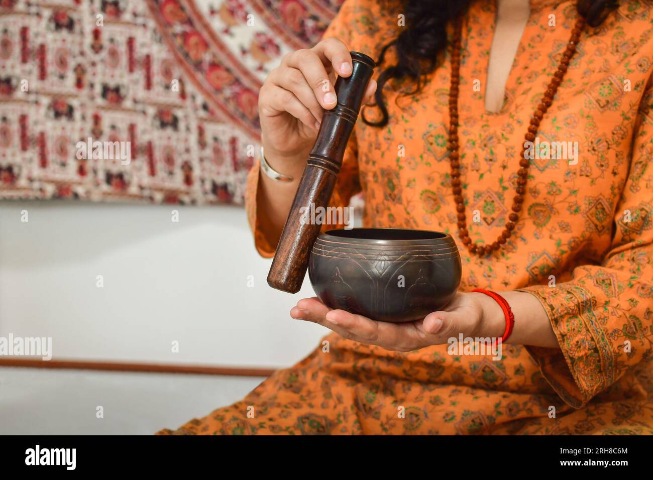 Une femme pratiquant la méditation et la guérison avec un bol chantant tibétain. Banque D'Images