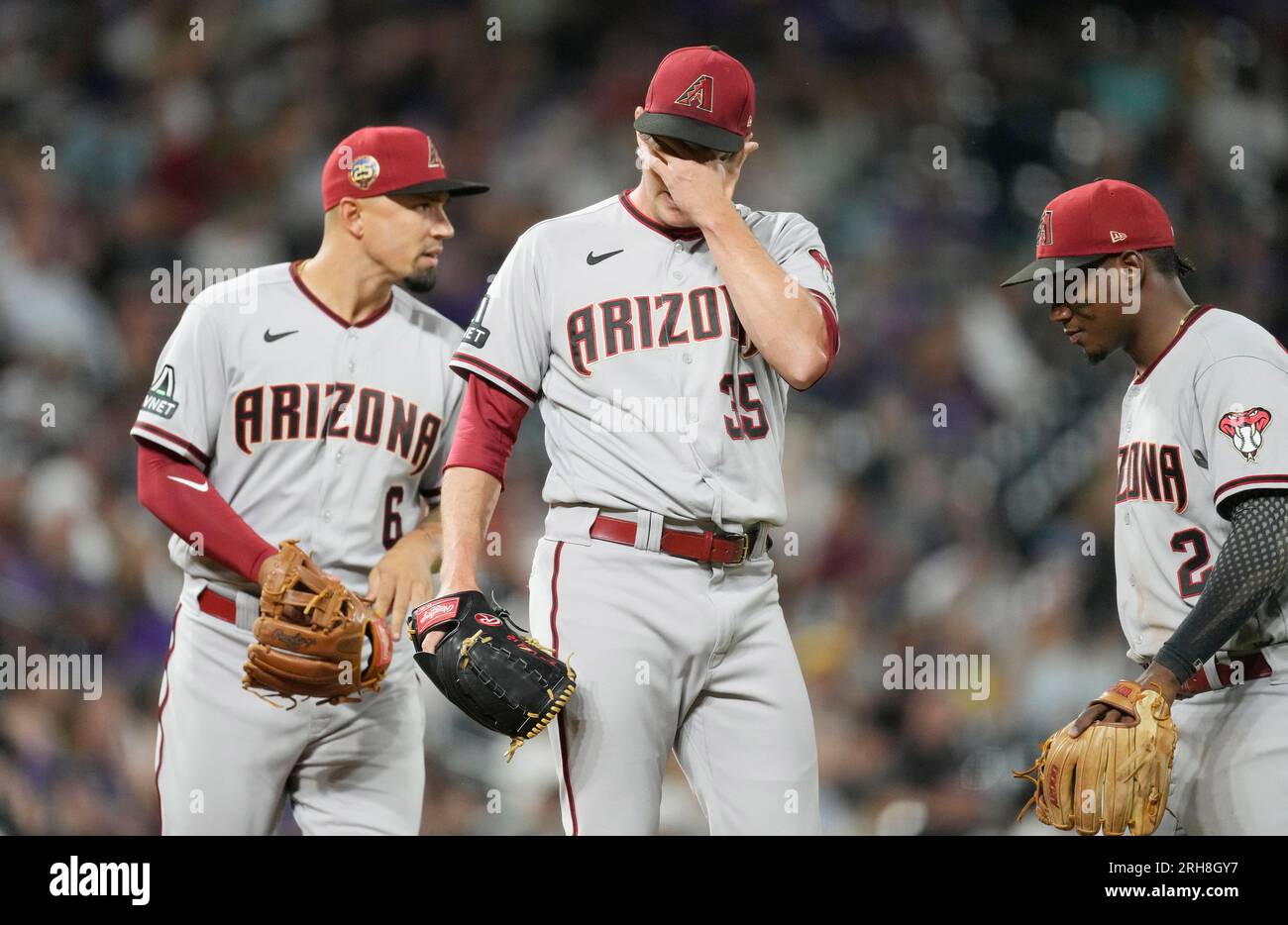 Arizona Diamondbacks relief pitcher Joe Mantiply, center, waits to be pulled from the mound after giving up three singles to the Colorado Rockies to load the bases in the eighth inning of a baseball game Monday, Aug. 14, 2023, in Denver. Diamondbacks third baseman Jace Peterson, left, and shortstop Geraldo Perdomo, right, look on. (AP Photo/David Zalubowski) Banque D'Images