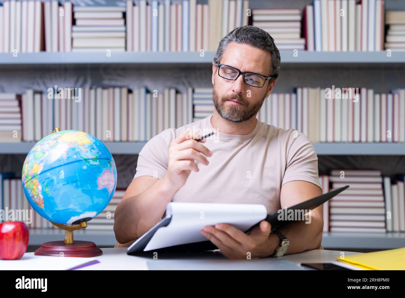 Journée des enseignants. Enseignant en classe scolaire. Connaissance et éducation avec un enseignant d'âge moyen. Professeur hispanique avec livre. Leçon d'enseignement de l'homme en classe Banque D'Images