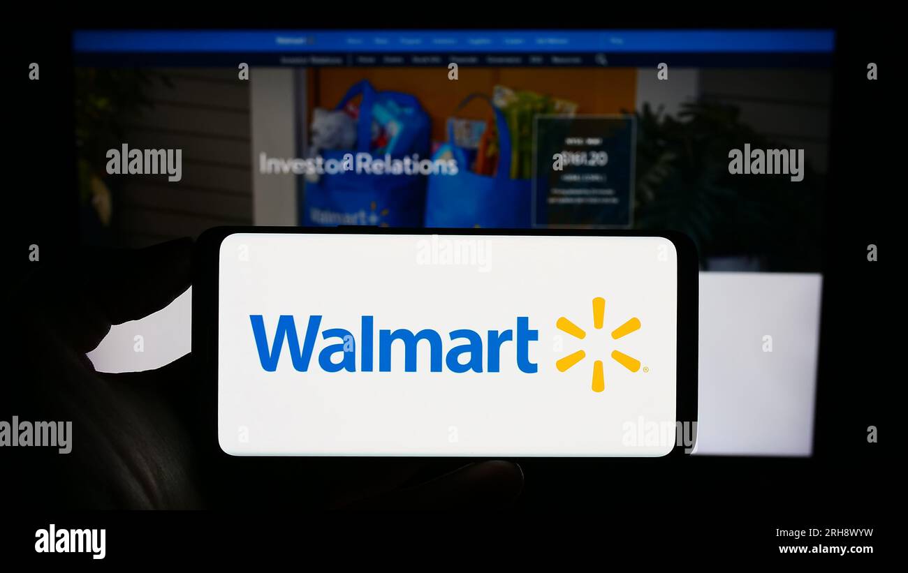 Personne tenant le téléphone portable avec le logo de la société de détail américaine Walmart Inc. Sur l'écran devant la page Web de l'entreprise. Concentrez-vous sur l'affichage du téléphone. Banque D'Images