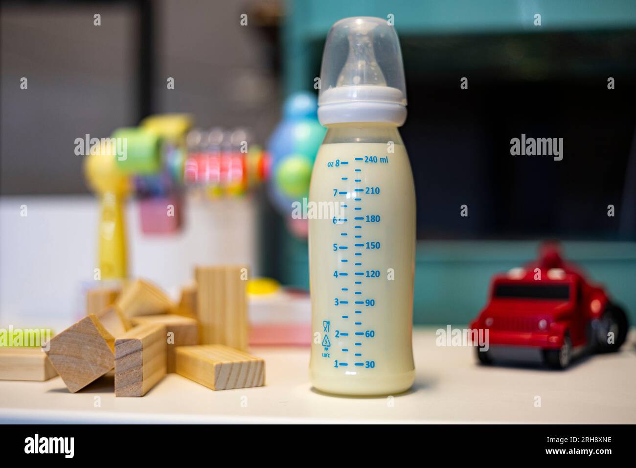 Les bouteilles de lait et les jouets pour enfants sont placés sur la table, arrière-plan pour l'annonce et le papier peint dans les accessoires et la scène de bébé. Images réelles dans la décoration Banque D'Images