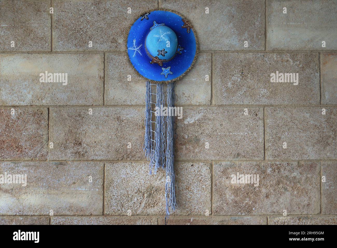 Un chapeau de paille bleu accroché à un mur. Banque D'Images