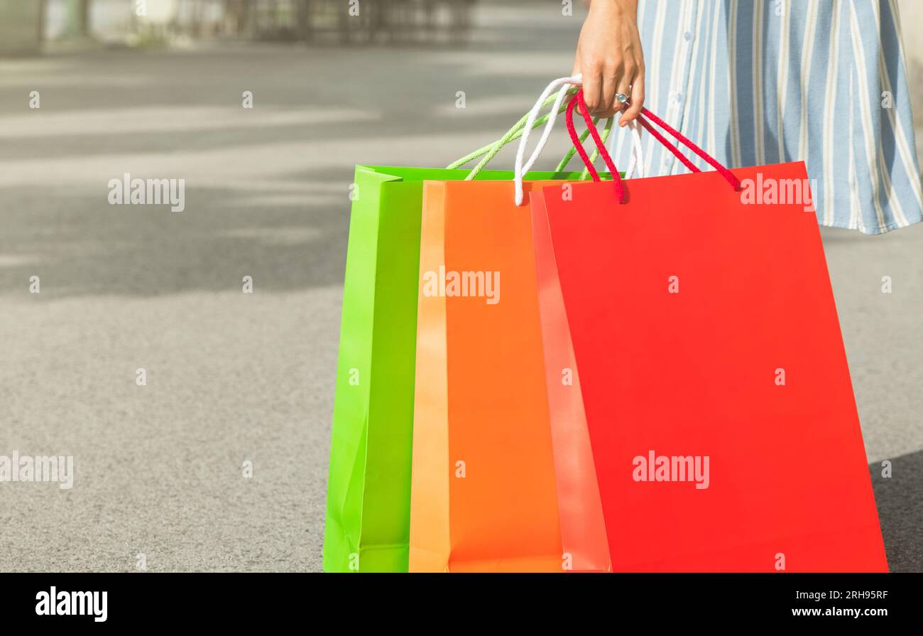 sacs à provisions en carton coloré dans la main féminine sur la rue Banque D'Images
