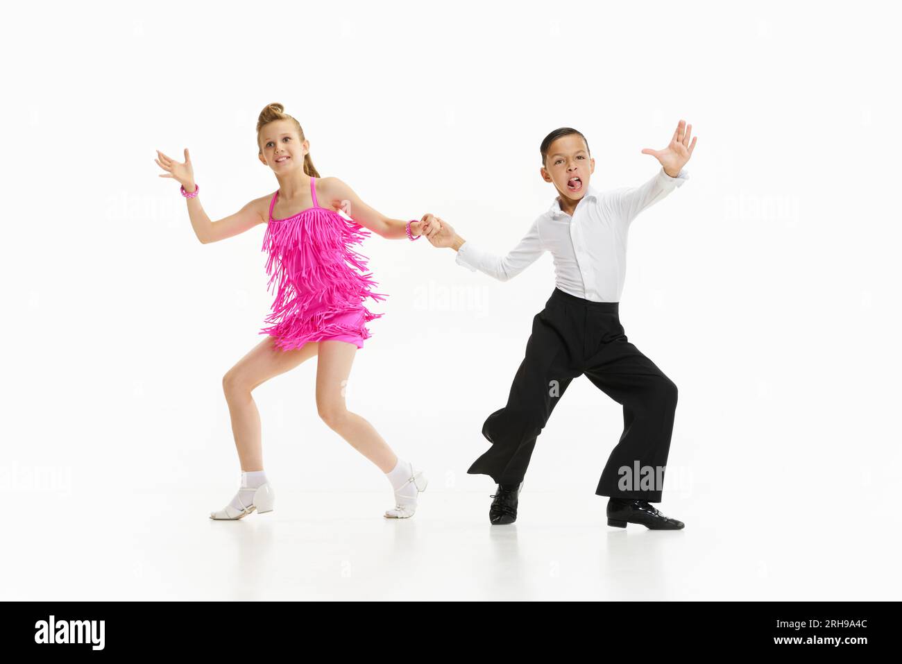 Petits enfants, beau garçon et fille en costumes de scène dansant style de danse rétro sur fond de studio blanc Banque D'Images
