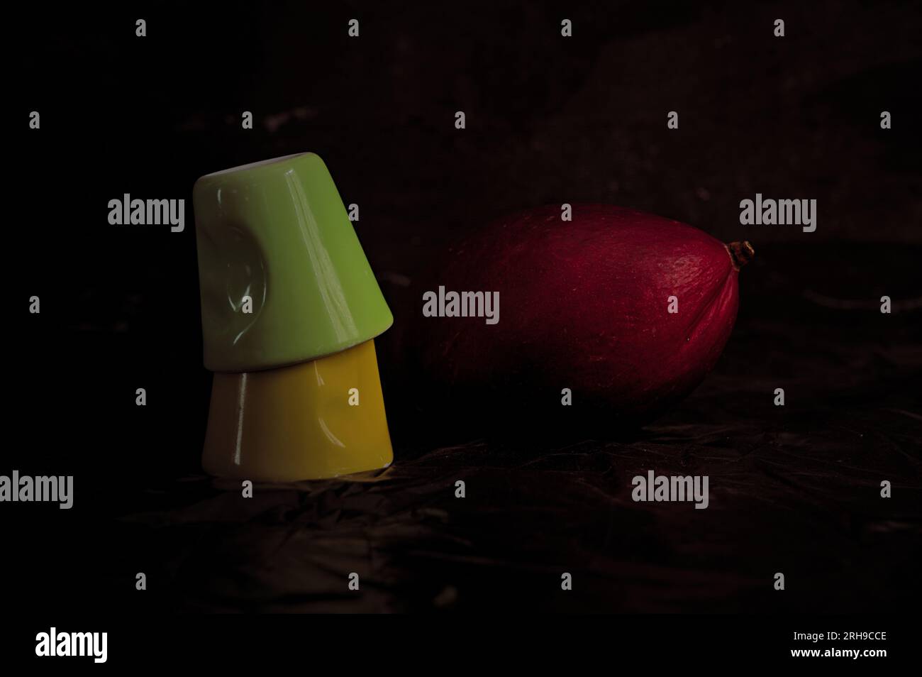 Nature morte avec 2 tasses de café et 1 mangues rouges. Couleurs saturées et fond sombre (image studio) Banque D'Images