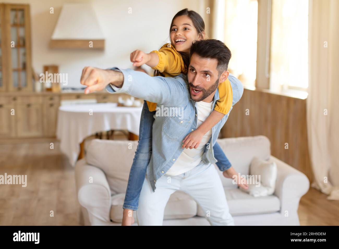Drôle papa coggybacking sa fille Kid faisant le geste de super-héros à l'intérieur Banque D'Images