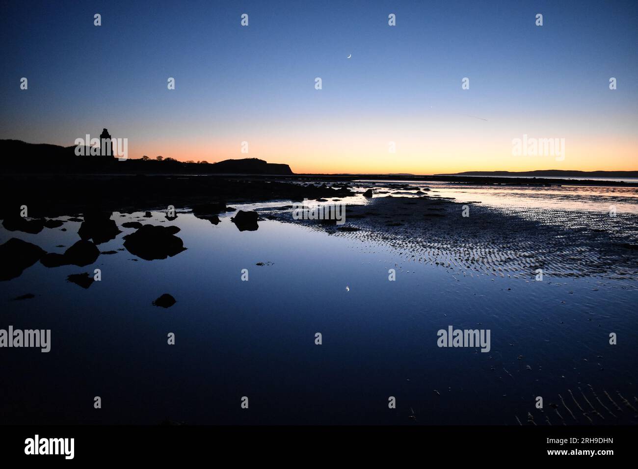 Coucher de soleil avec reflet de la lune surplombant le château de Greenan au crépuscule Banque D'Images