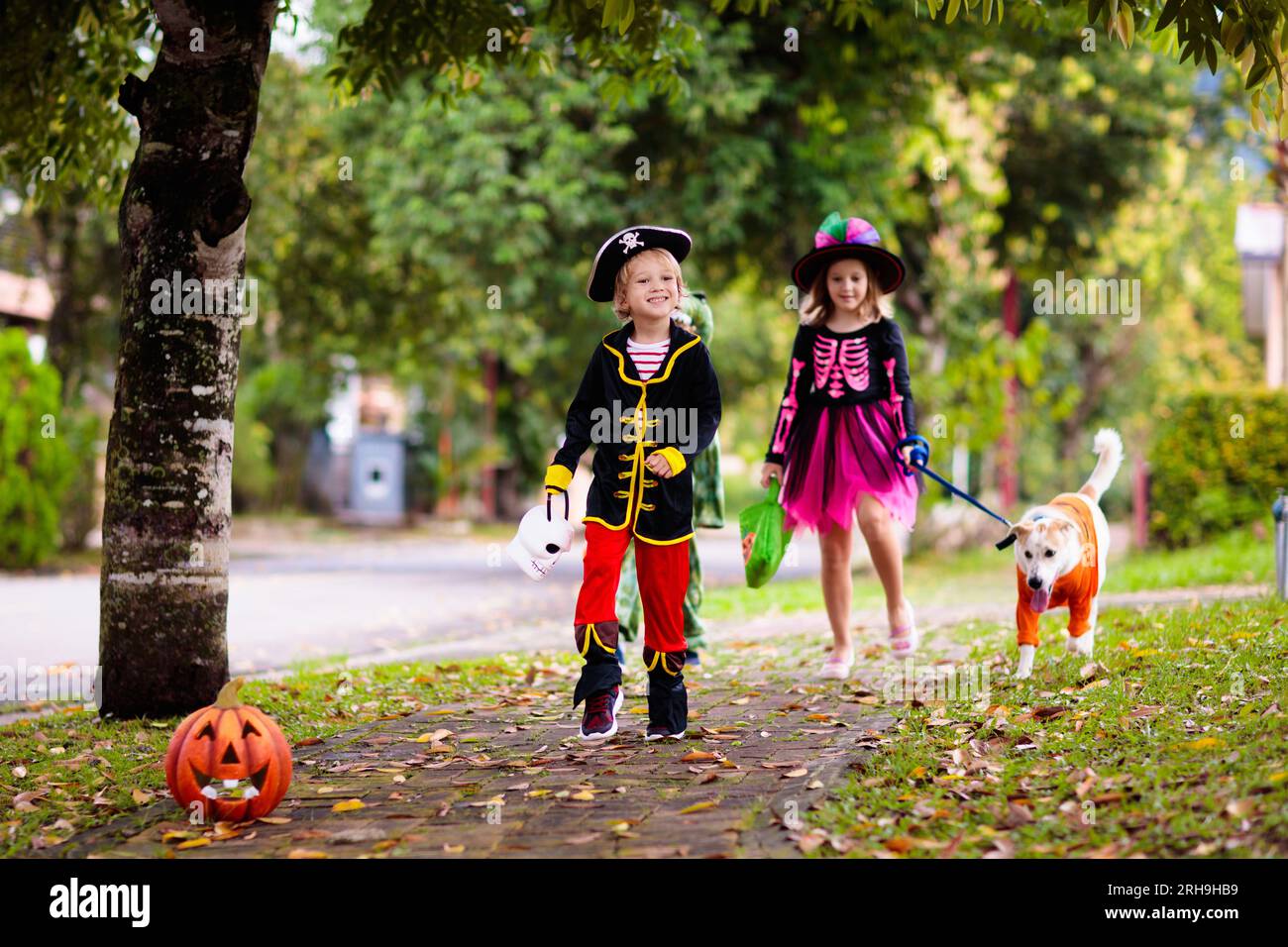 Les enfants se déguent en costume d'Halloween. Les enfants de couleur s'habillent avec un seau à bonbons dans la rue de banlieue. Petit garçon et fille trick ou traitement Banque D'Images