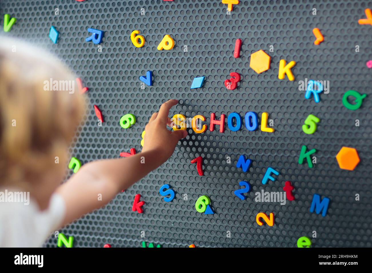 Garçon épelant le mot école. Lettres magnétiques sur tableau noir dans la classe préscolaire ou maternelle. Les enfants apprennent l'alphabet. Banque D'Images