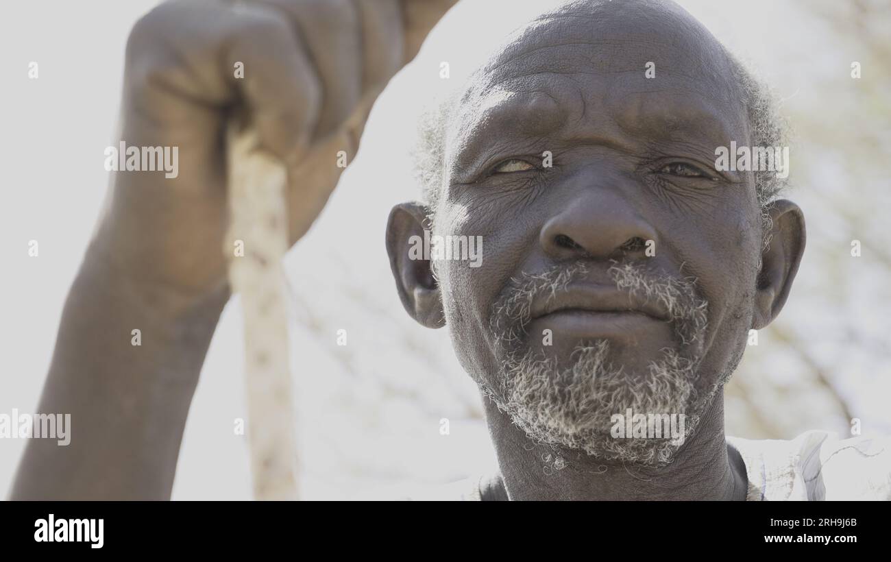 Mali- dirigeant de village africain aîné avec un œil blanc aveugle tenant une canne Banque D'Images