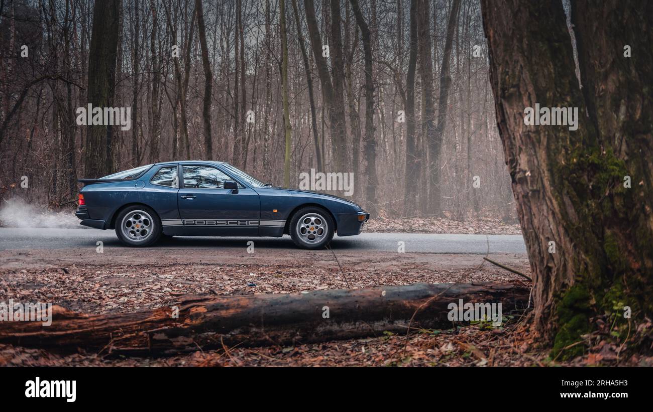 Porsche 944 bleu foncé dans la forêt d'automne. Vue de profil latérale de la voiture de sport des années 1980. Banque D'Images