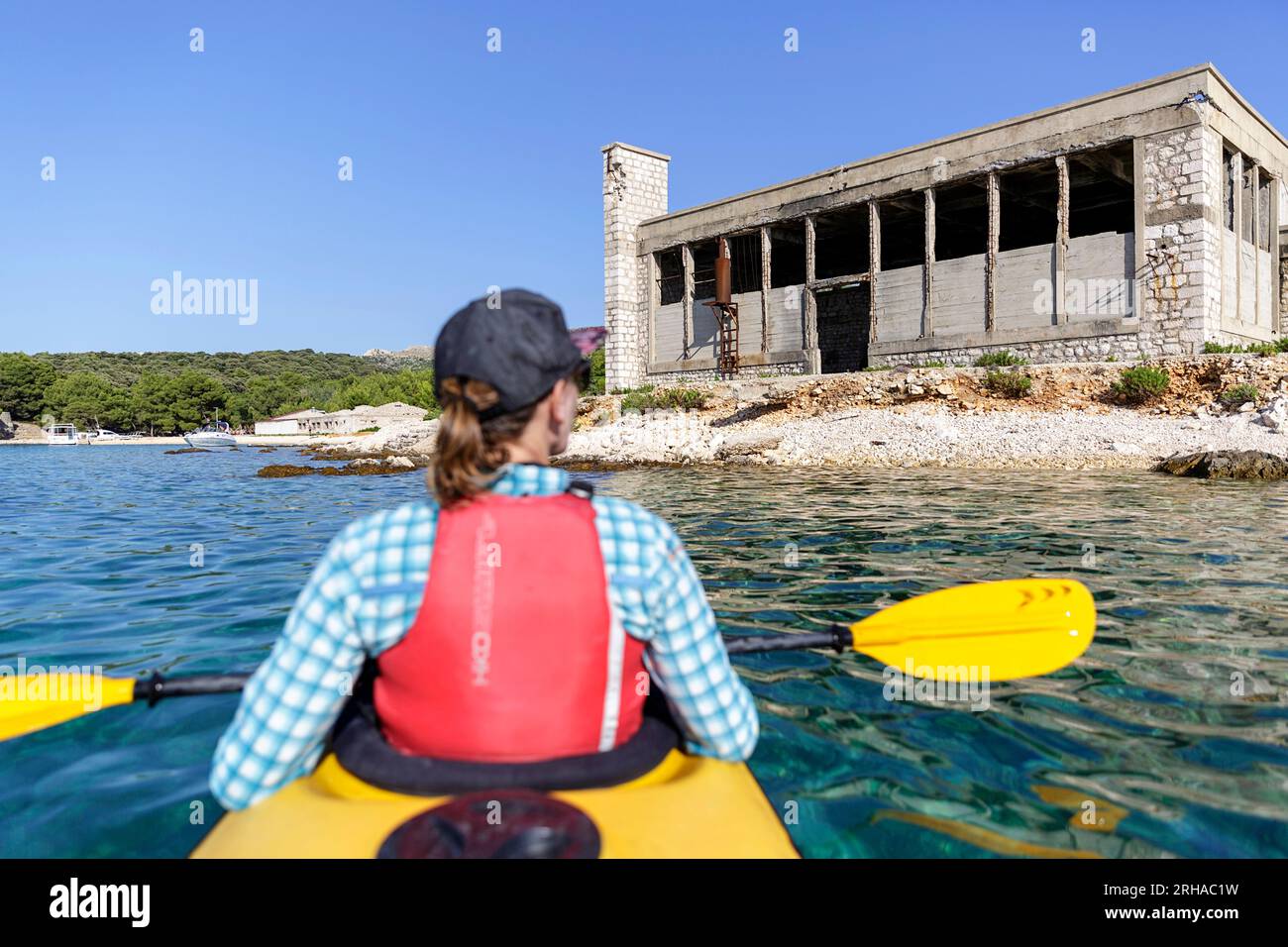 Une femme, touriste, kayakiste de mer regardant les restes de la prison de femmes abandonnées de l'époque yougoslave sur l'île Saint Grégoire dans la mer Adriatique, Croatie Banque D'Images