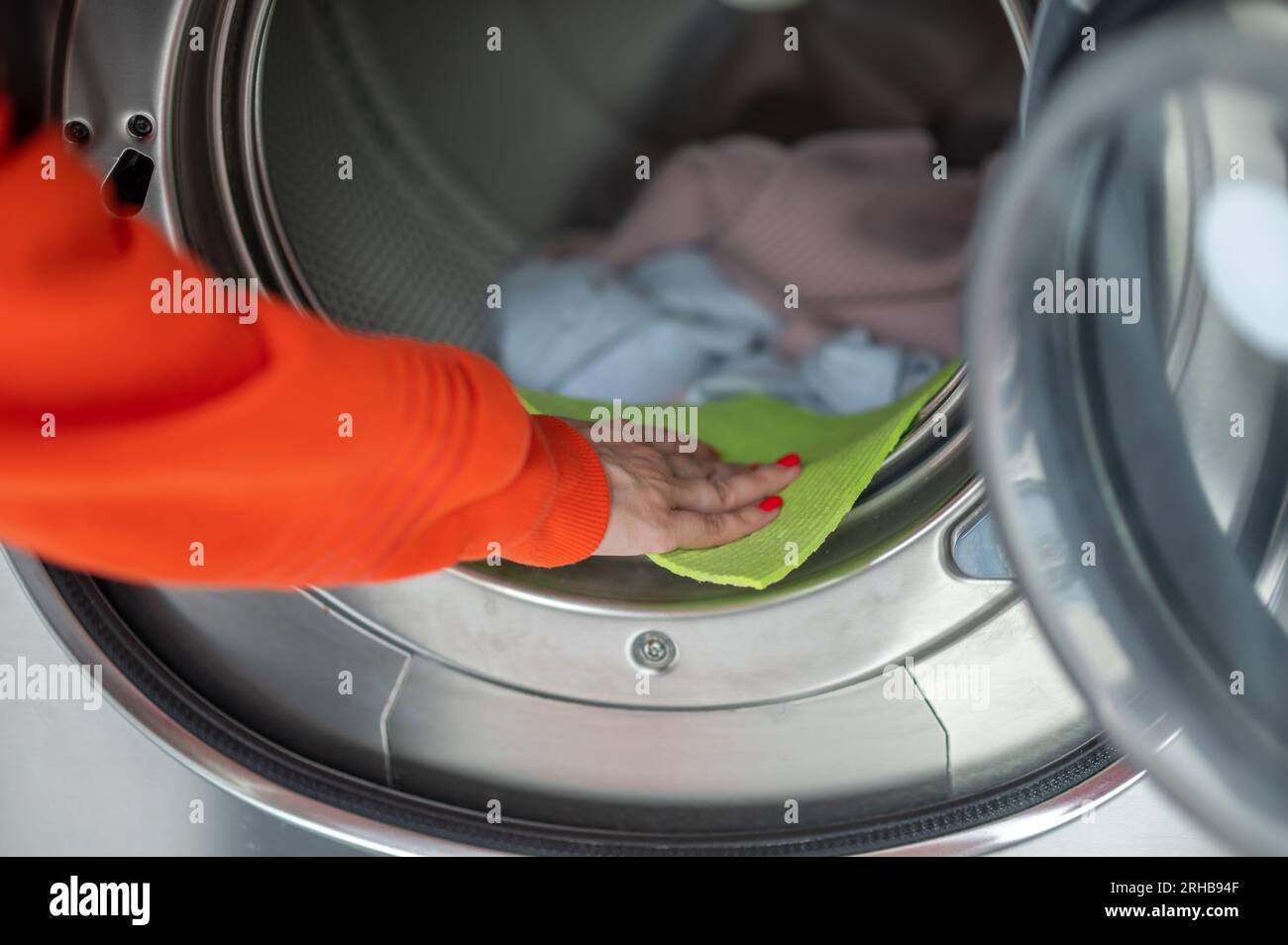 Femme laver les vêtements sales, nettoyer la machine à laver avec un chiffon dans la salle de lavage. Banque D'Images