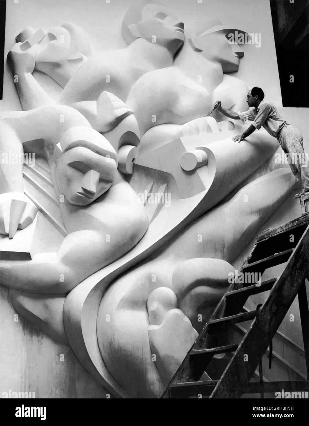New York, New York : 1940 Isamu Noguchi travaille sur l'Associated Press Building plaque, qui a été sculptée dans le plâtre et coulée en acier inoxydable - à l'époque la plus grande coulée d'acier inoxydable jamais réalisée. Il est toujours installé au Rockefeller Center. Banque D'Images