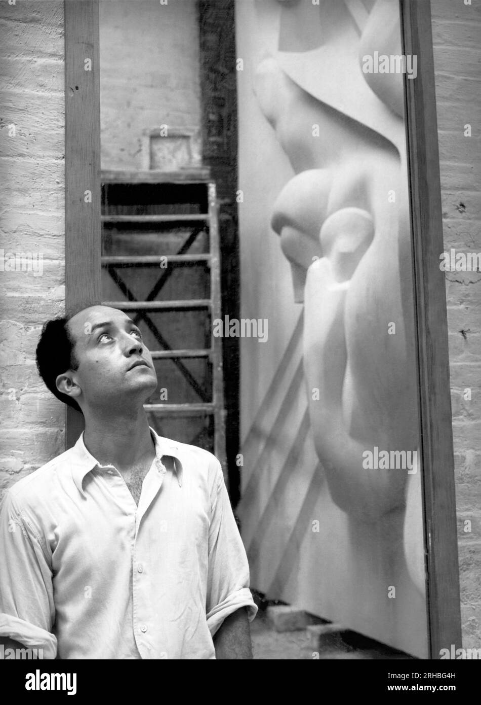 New York, New York : 1940 Isamu Noguchi avec un reflet de l'Associated Press Building plaque, qui a été sculpté dans le plâtre et coulé en acier inoxydable - à l'époque la plus grande coulée d'acier inoxydable jamais réalisée. Il est toujours installé au Rockefeller Center. Banque D'Images