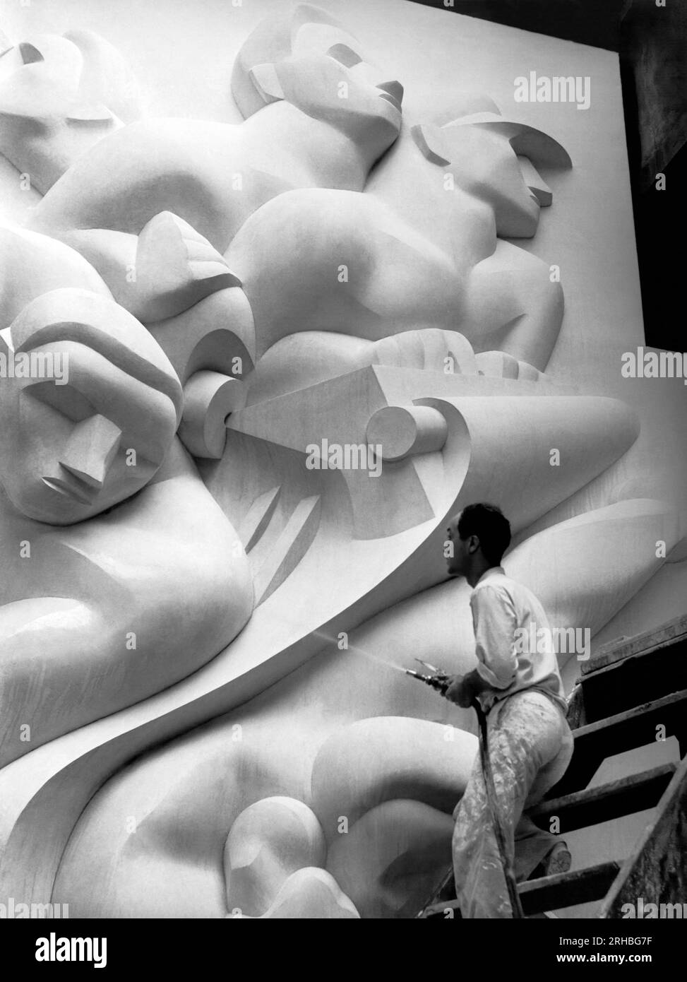 New York, New York : 1940 Isamu Noguchi travaille sur l'Associated Press Building plaque, qui a été sculptée dans le plâtre et coulée en acier inoxydable - à l'époque la plus grande coulée d'acier inoxydable jamais réalisée. Il est toujours installé au Rockefeller Center. Banque D'Images