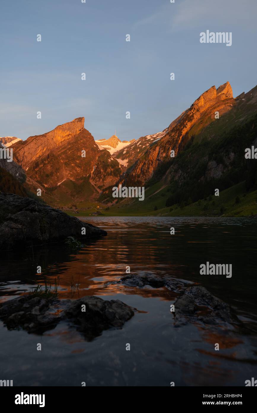 Lever de soleil épique par un lac alpin en Suisse appelé Seealpsee. Le soleil brille au sommet de la montagne de l'autre côté du lac. Banque D'Images