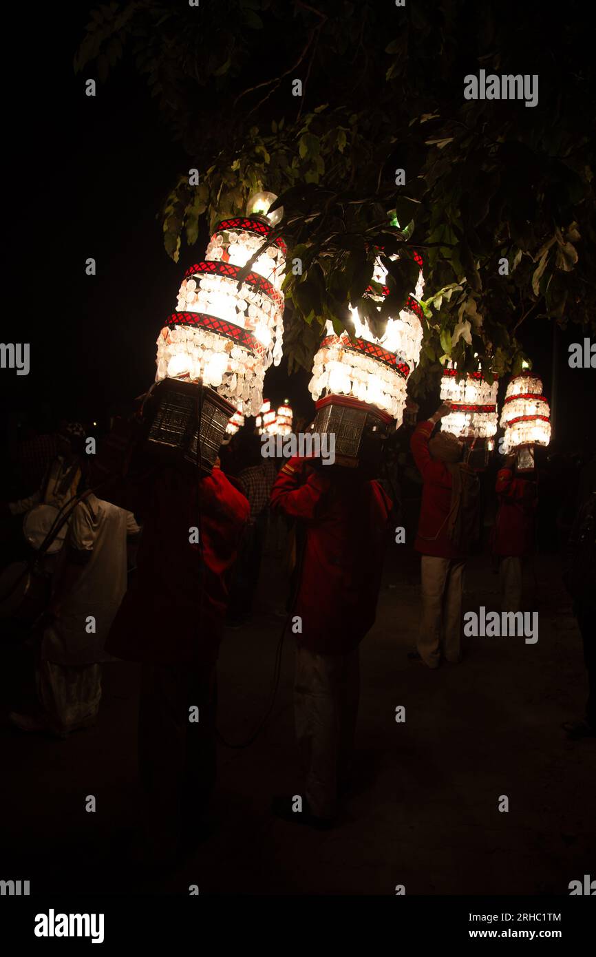 Vue arrière de quatre hommes portant des lustres traditionnels dans une procession de mariage traditionnelle, New Delhi, Inde Banque D'Images