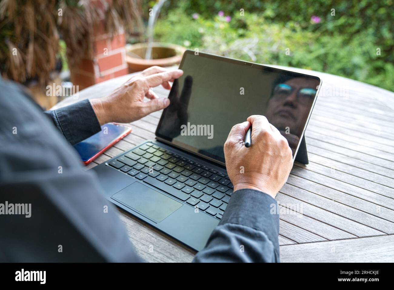 Homme d'affaires travaillant sur sa tablette, vue rapprochée. Au patio, face au jardin. Banque D'Images
