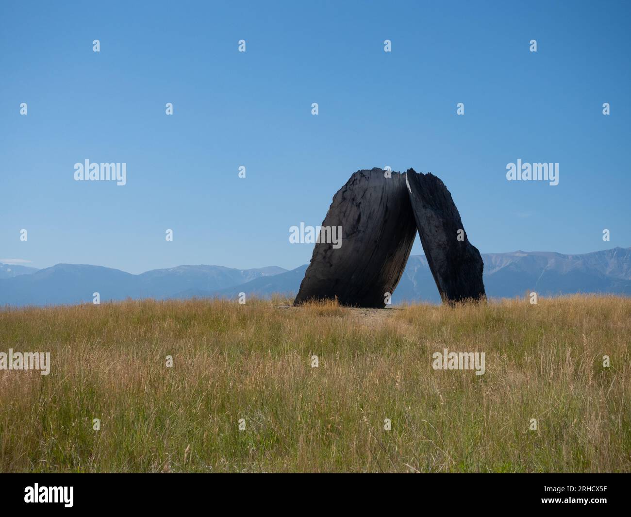 La sculpture Inverted Portal conçue par Ensamble Studio et construite par OSM, avec la chaîne de montagnes Beartooth au loin et un champ herbeux Banque D'Images