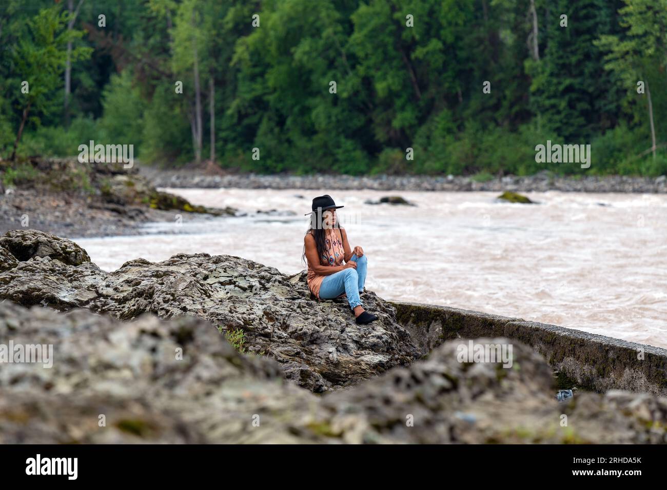 Première nation autochtone canadienne Wet'suwet'en Femme observant les gens pêcher le saumon dans la rivière Bulkley, Witset Canyon, Colombie-Britannique, Canada. Banque D'Images