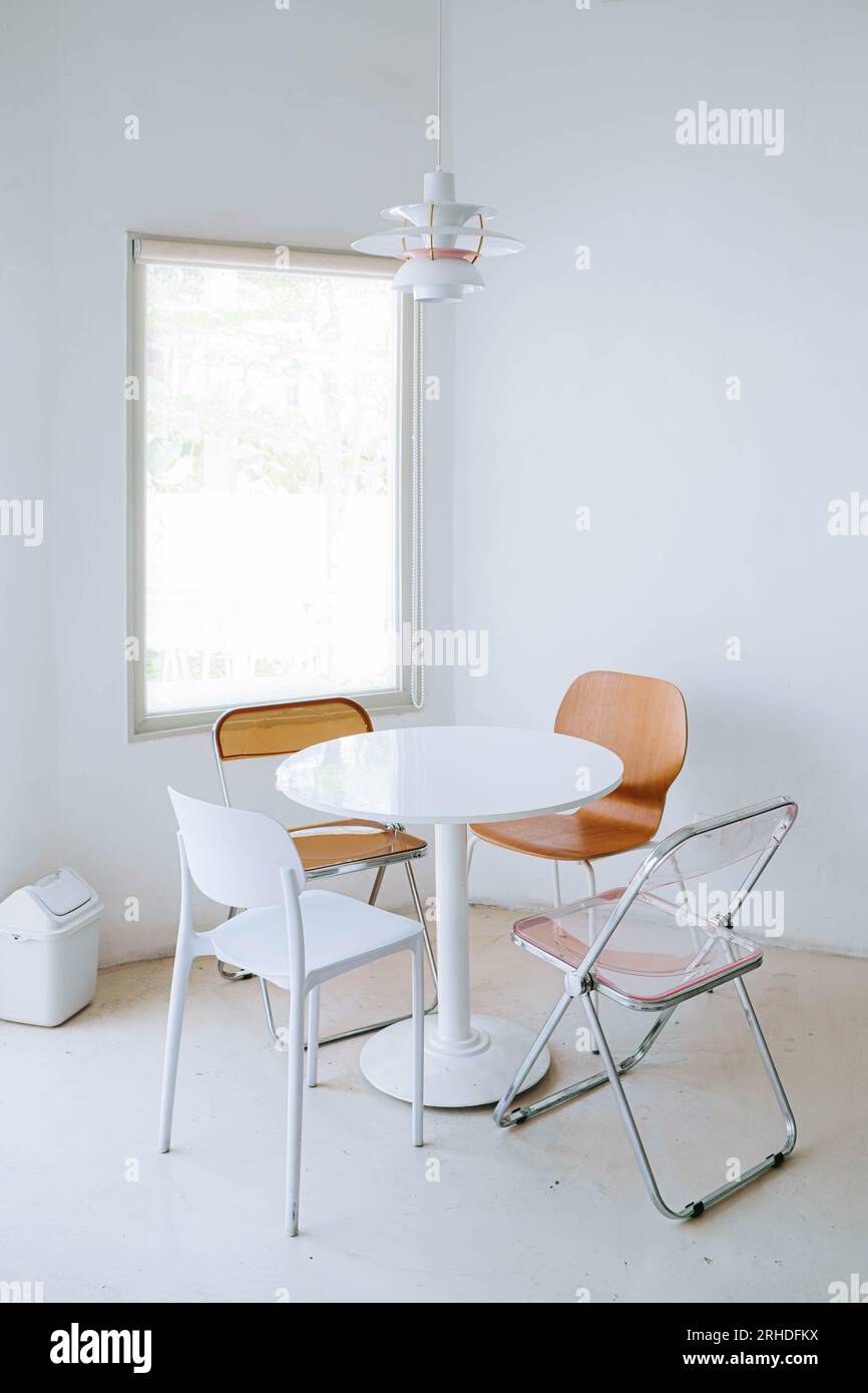 Portrait ou plan vertical de l'intérieur minimaliste et chaleureux du café contient une chaise à manger en plastique, une fenêtre, une poubelle minimaliste et 4 chaises Banque D'Images