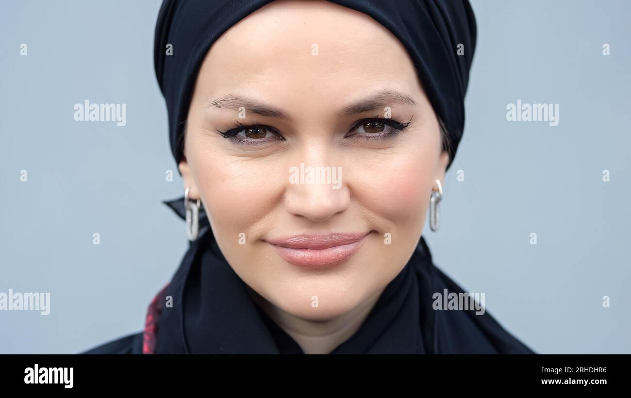 Femme musulmane en hijab noir regarde avec une expression souriante Banque D'Images